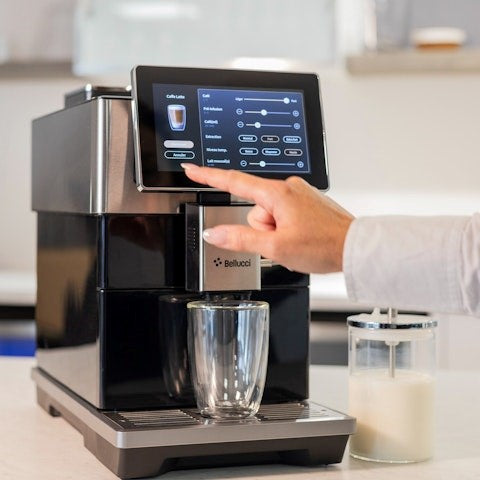 Person using a Bellucci coffee machine with a touch screen display in a kitchen setting.