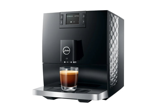 Black and silver Jura coffee machine with a glass of coffee on a white background