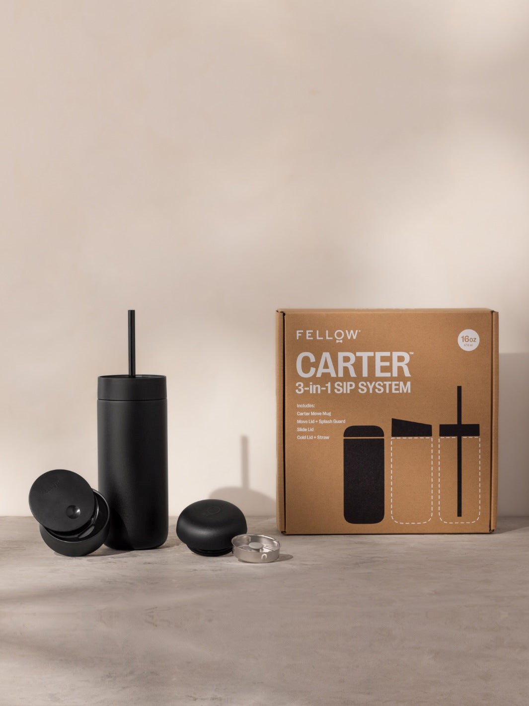 Black tumbler with accessories and Fellow Carter 3-in-1 SIP System packaging on a beige background
