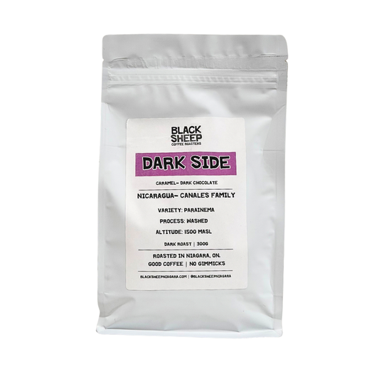 A white stand-up pouch of Black Sheep Coffee Roasters Dark Side coffee, featuring a white label with black text and a purple accent block, set against a plain white background.