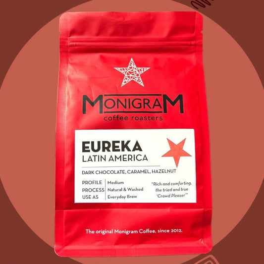 Red coffee bag with 'Monigram Coffee Roasters' branding on a brown background