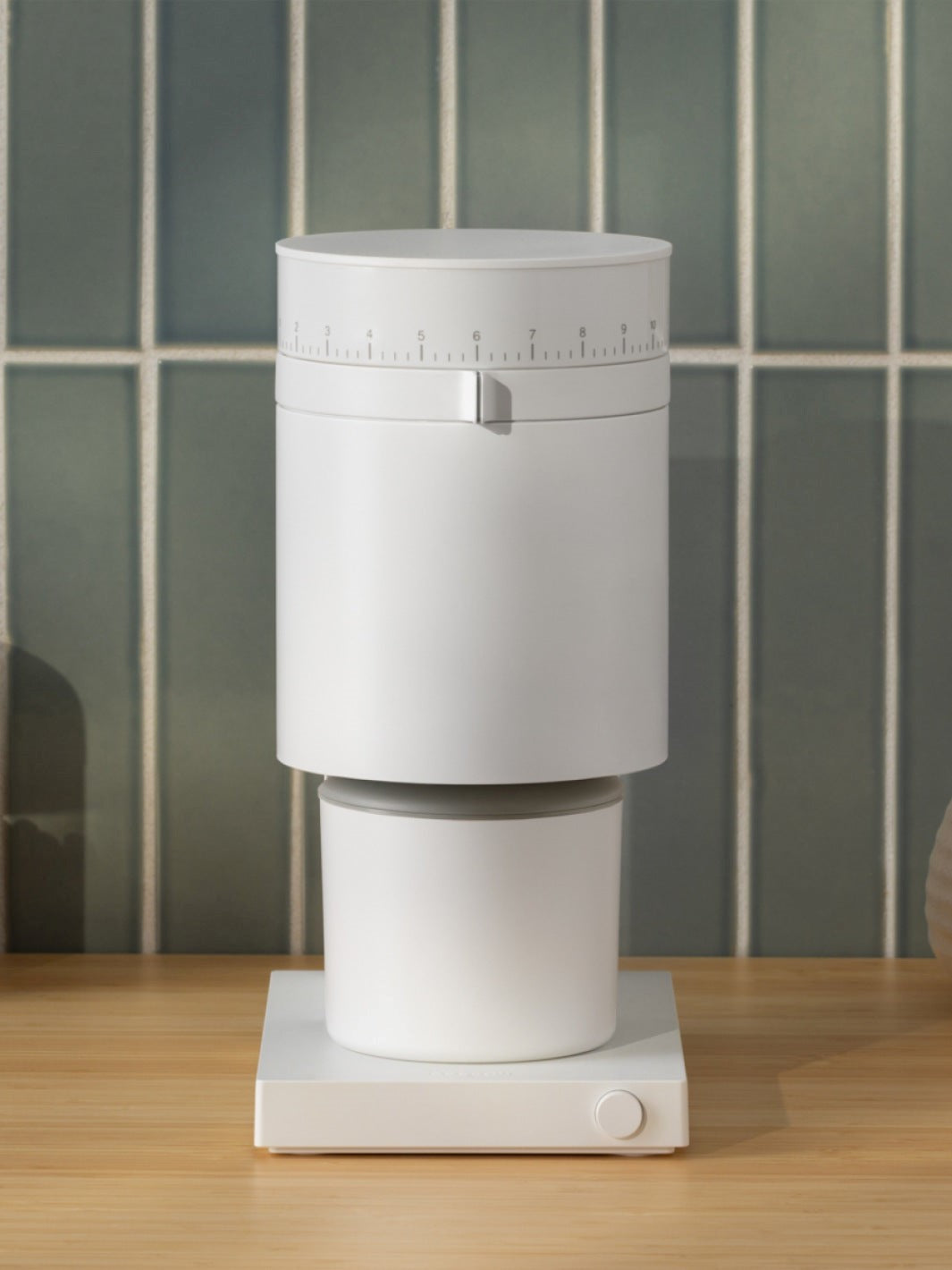 Matte White coffee grinder on a wooden surface with tiled wall background