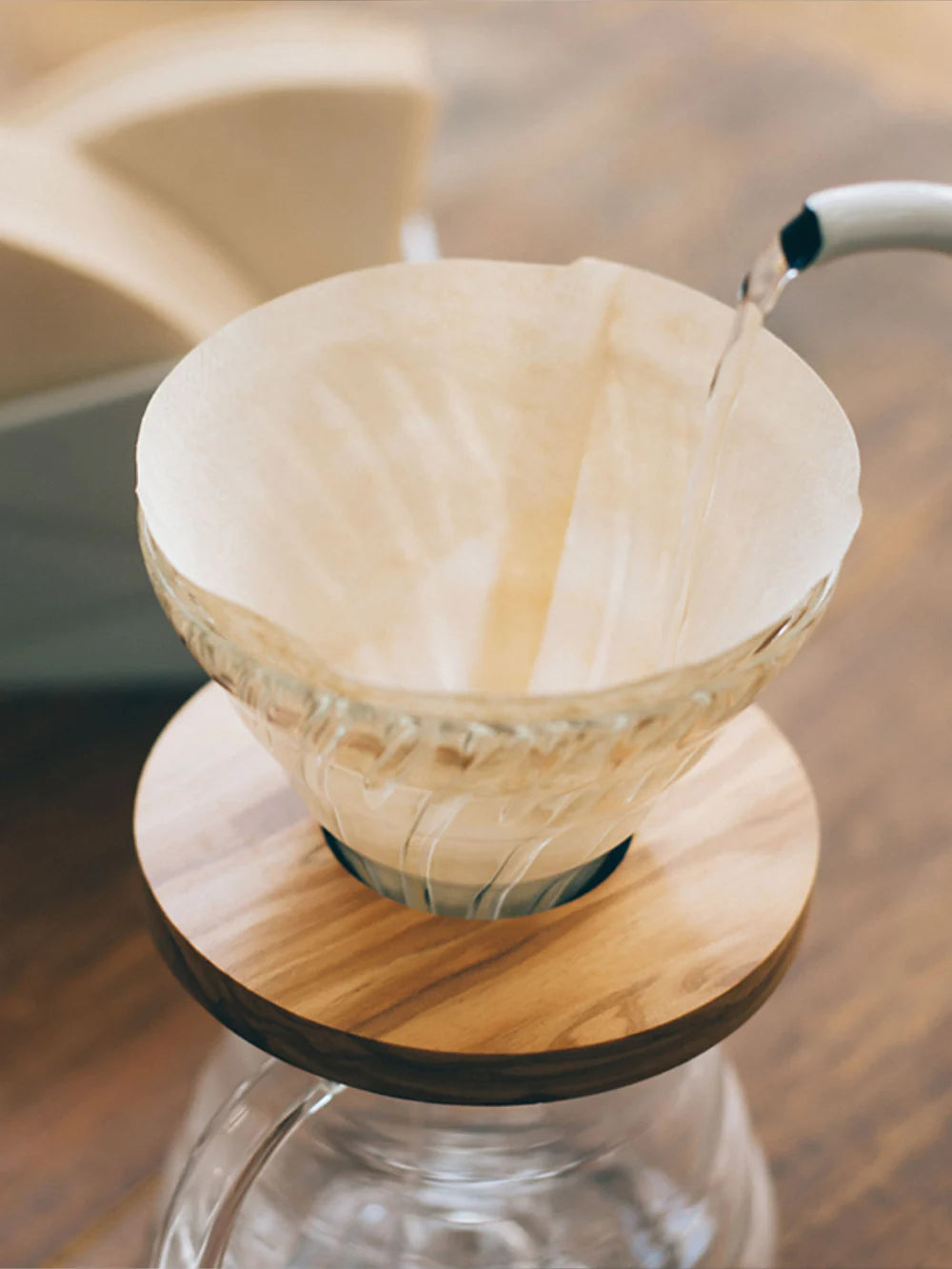Paper coffee filter on a glass coffee maker with a blurred background