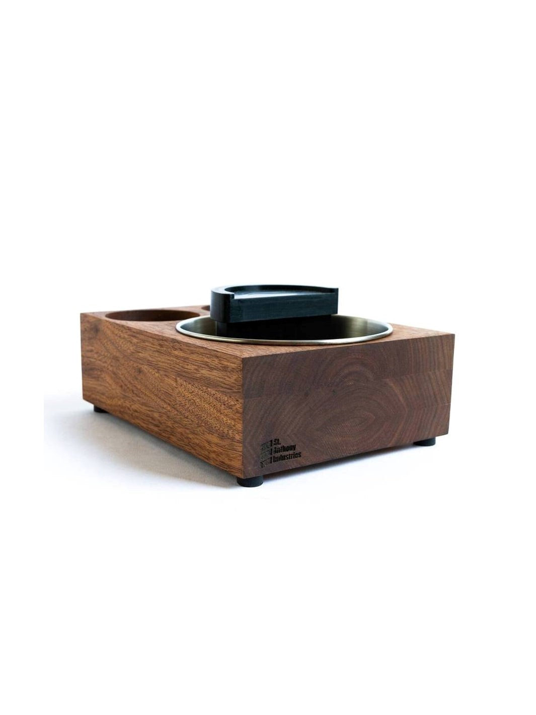 A brown wooden espresso knock box and tamp station with a stainless steel knock box reservoir and a black plastic tamping stand.