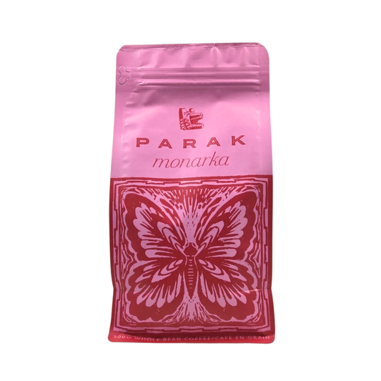 A pink and red stand-up pouch of Parak Monarka coffee beans, featuring a butterfly graphic on the front, set against a plain white background.