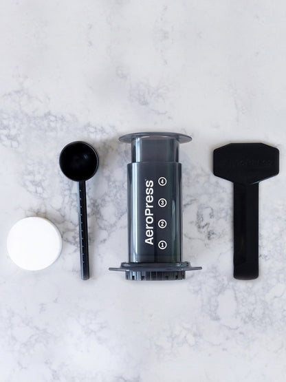Aeropress coffee maker components on a marble surface
