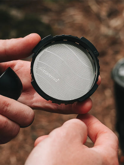 Person holding a coffee filter with a blurred natural background