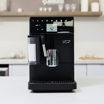 Black coffee machine labeled 'Latte de Luxe' on a kitchen counter.