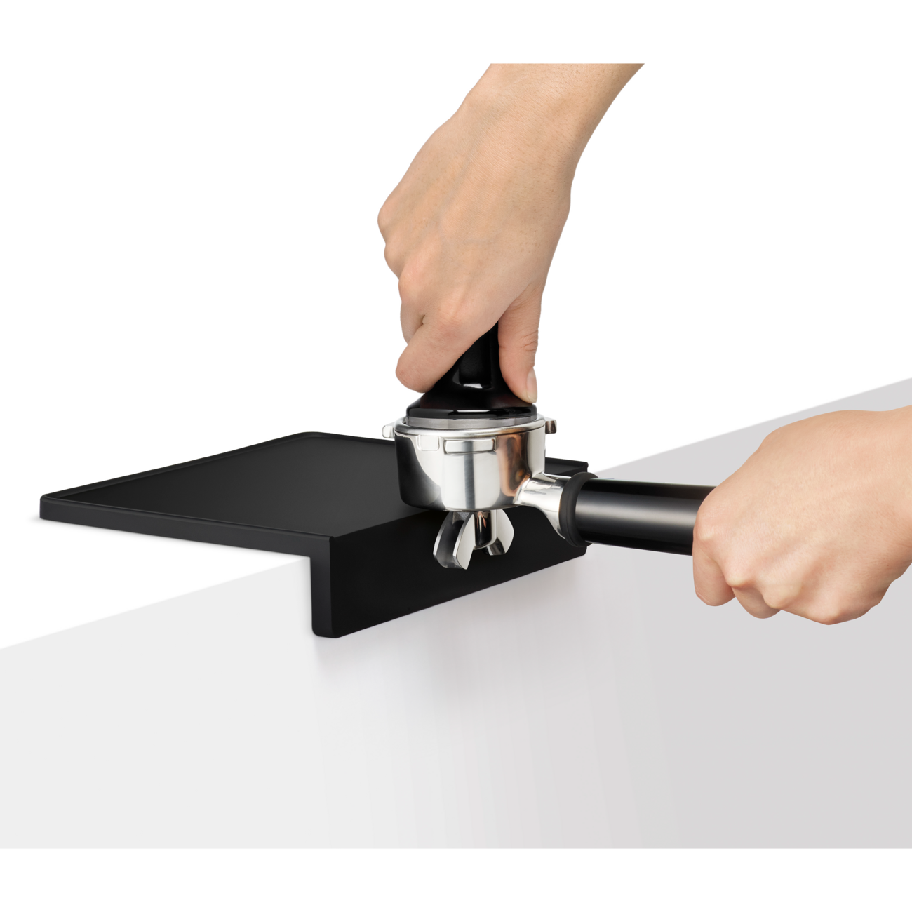 Person using a black and silver coffee tamping device on a white surface