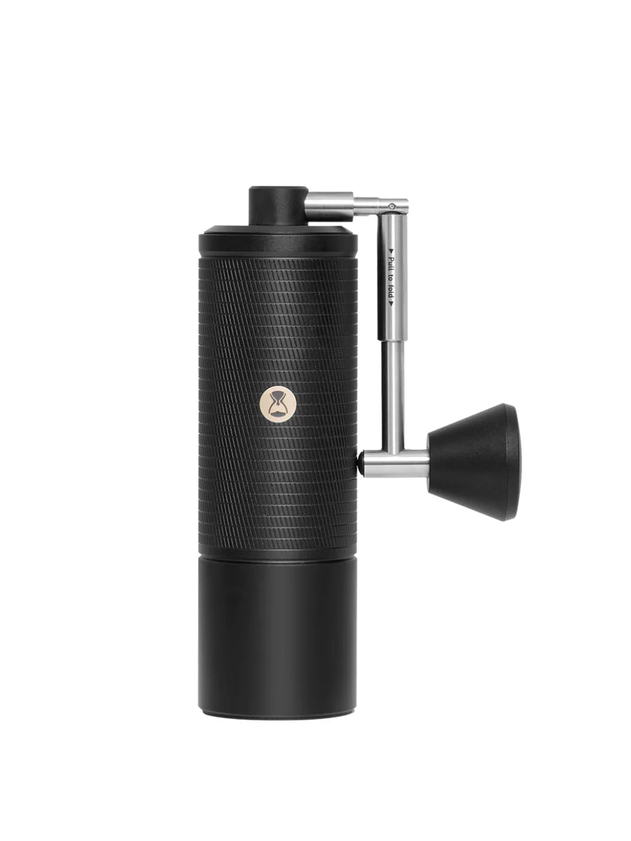 Black manual coffee grinder with a silver handle on a white background