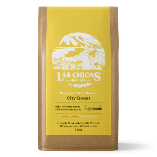 A 340g bag of Las Chicas del Cafe City Roast coffee in a brown kraft paper bag with a bright yellow label, shown against a plain white background.