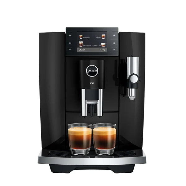 A black Jura E6 coffee machine with two glass cups of espresso on the drip tray, shown against a solid white background.
