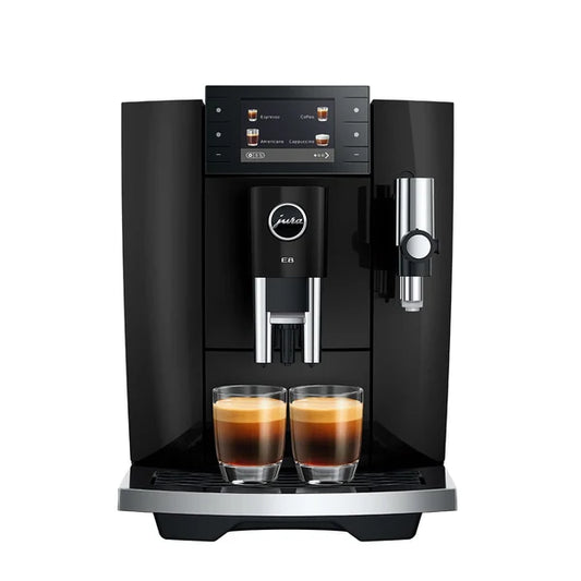 A black Jura E6 coffee machine with two glass cups of espresso on the drip tray, shown against a solid white background.