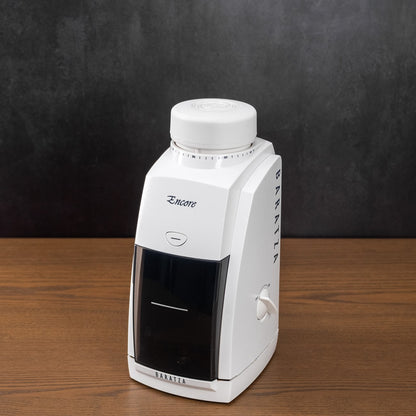 White humidifier with black base on a wooden surface against a dark background