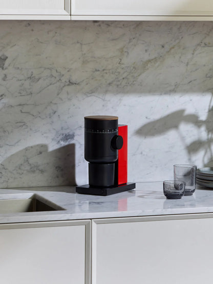 A black and red modern coffee grinder in a white marble modern kitchen.