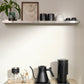 Black Fellow Stagg Gooseneck Kettle with Black Fellow Opus Coffee Grinder on a wooden surface with a shelf in the background.