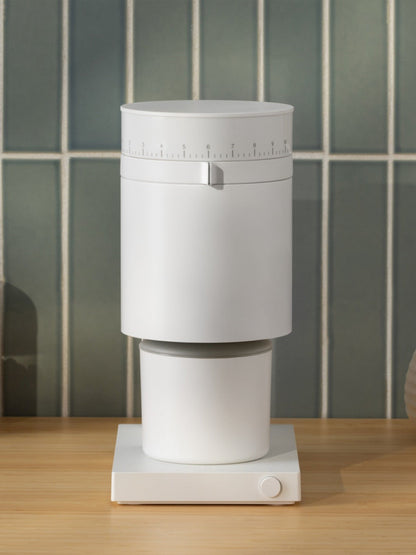 Matte White coffee grinder on a wooden surface with tiled wall background