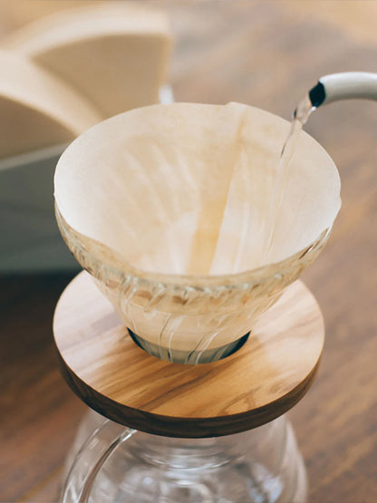 Paper coffee filter on a glass coffee maker with a blurred background
