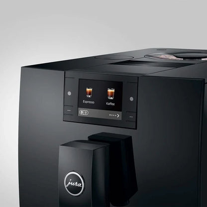 A close-up of a black Jura coffee machine showing its digital touch display screen with espresso and coffee icons, set against a clean light gray background.