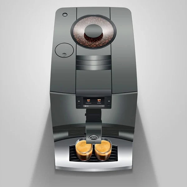 A sleek, dark gray automatic espresso machine with a bean hopper on top and two cups of espresso brewing underneath, set against a light gray background.