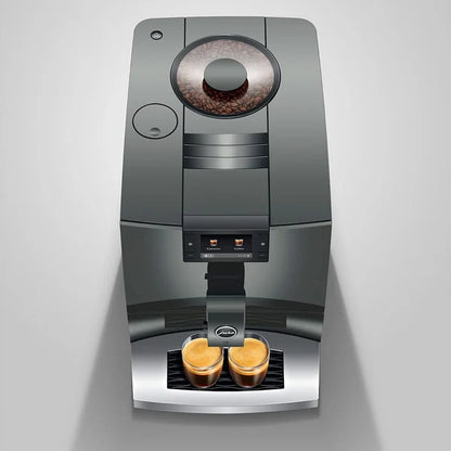 A sleek, dark gray automatic espresso machine with a bean hopper on top and two cups of espresso brewing underneath, set against a light gray background.