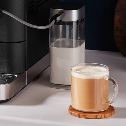Coffee machine with milk carafe and glass of coffee on a white surface