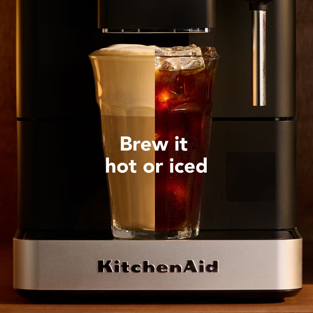 KitchenAid coffee machine with a glass of hot and iced coffee on a wooden surface.