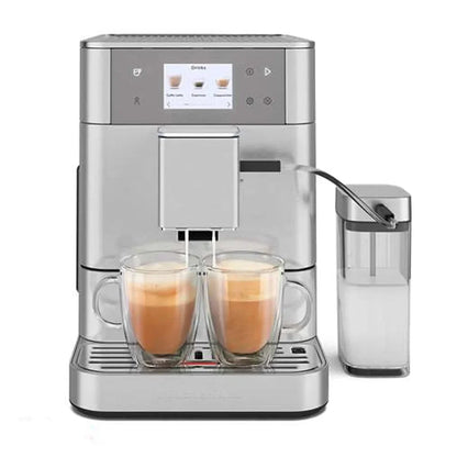 A silver espresso machine with two glass mugs filled with coffee and a clear milk container on a white background.