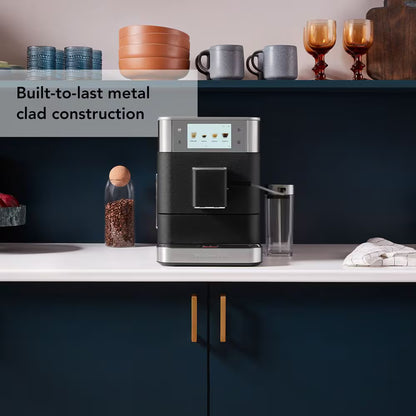 Modern coffee machine on a kitchen counter with text about metal clad construction.
