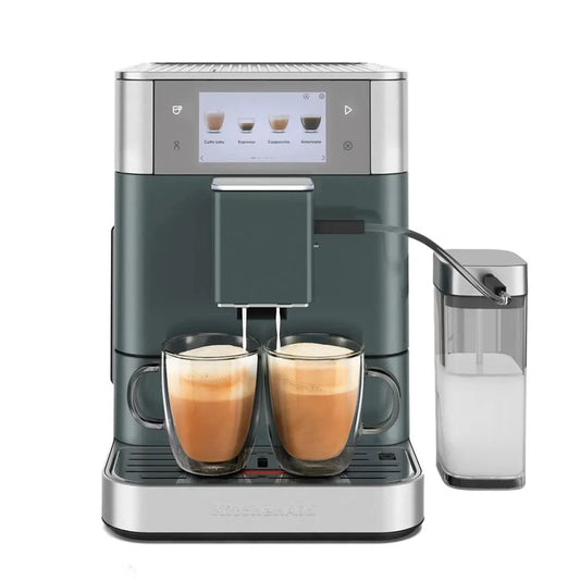A milk-based coffee machine, in a dark slate green and stainless steel finish. Two glass mugs filled with cappuccino are shown under the spout, and a separate milk container is positioned to the right.