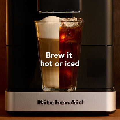 Half a hot latte and half an iced coffee pictured together to look like one beverage, sitting on a coffee maker with white text "Brew it hot or iced".
