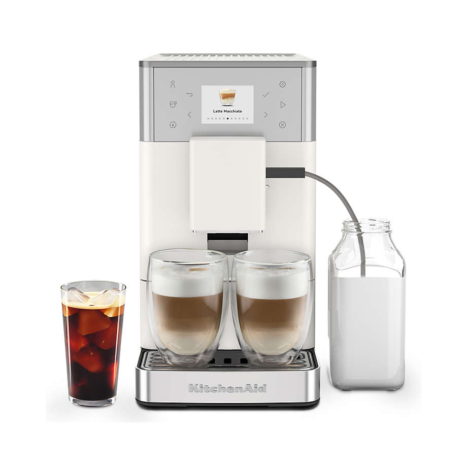 KitchenAid coffee machine with glasses of coffee and a bottle of milk on a white background