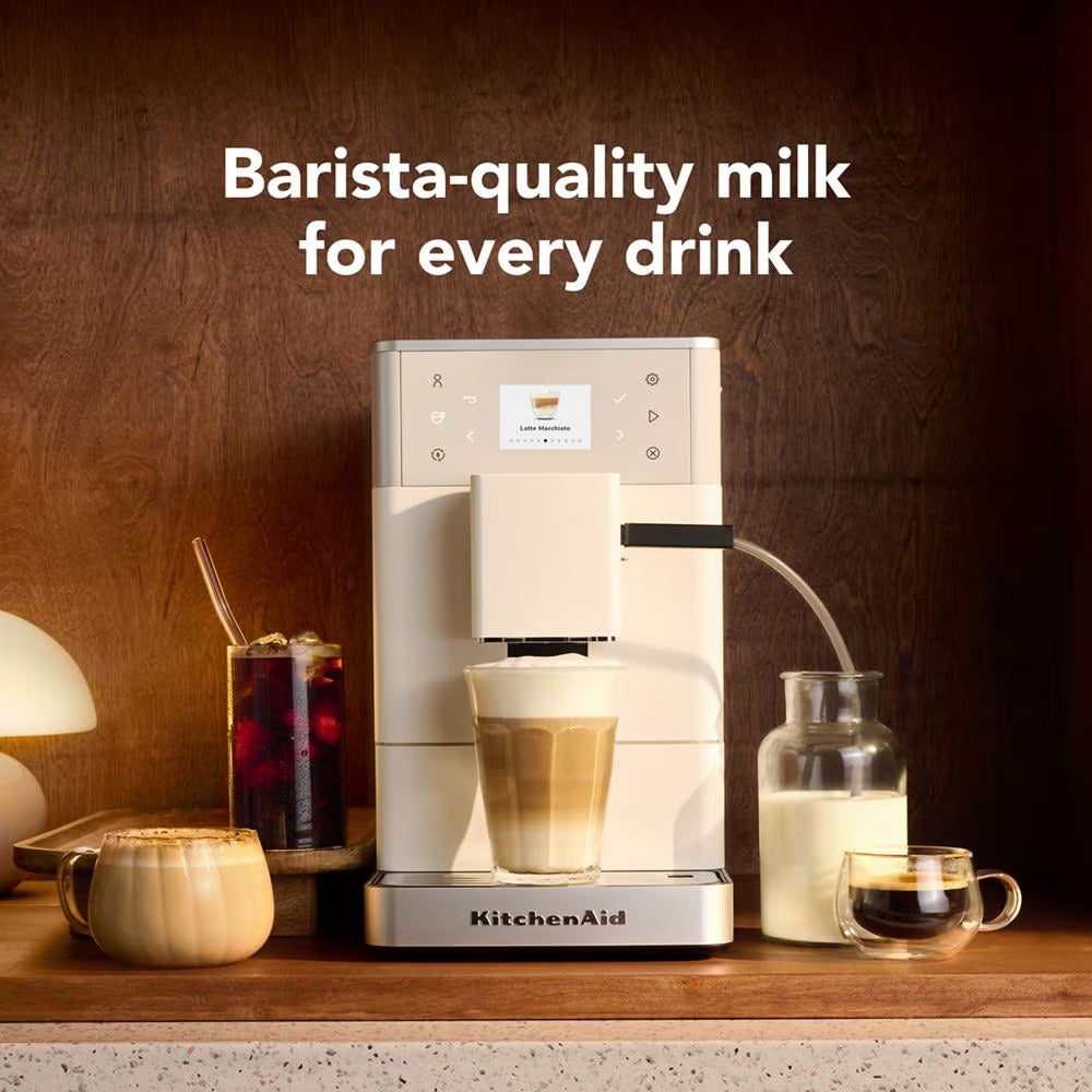 KitchenAid coffee machine with a glass of milk and a cup of coffee on a wooden surface.