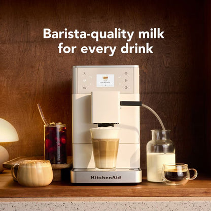 KitchenAid coffee machine with a glass of milk and a cup of coffee on a wooden surface.