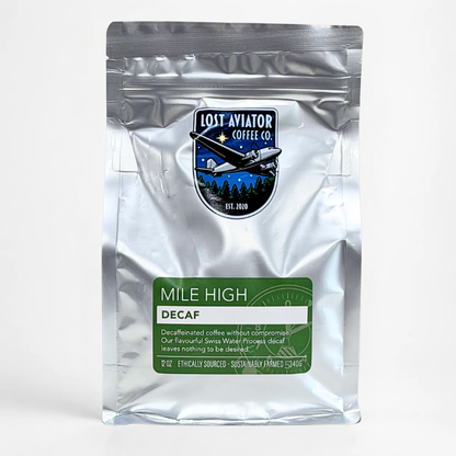 A silver resealable coffee bag with a green and white label reading 'Mile High Decaf' and a Lost Aviator Coffee Co. logo patch near the top, photographed on a clean white background.