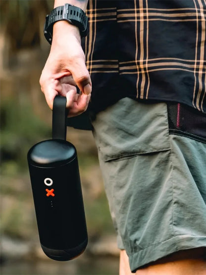 Person holding a black portable coffee grinder outdoors