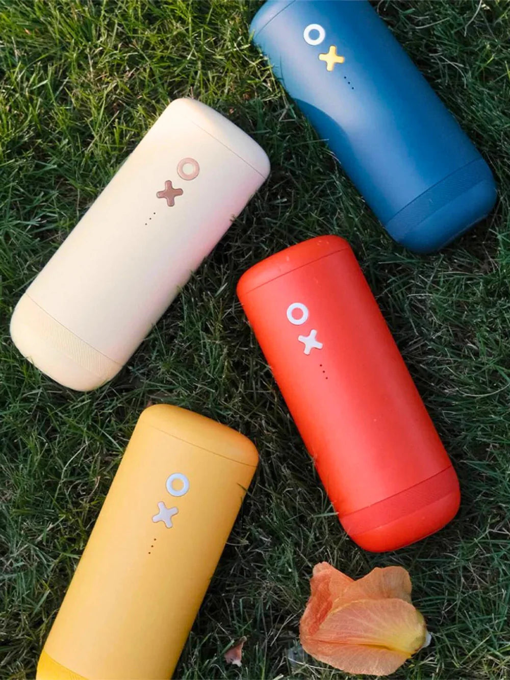 Four colorful coffee grinders with X and circle designs on a grassy background