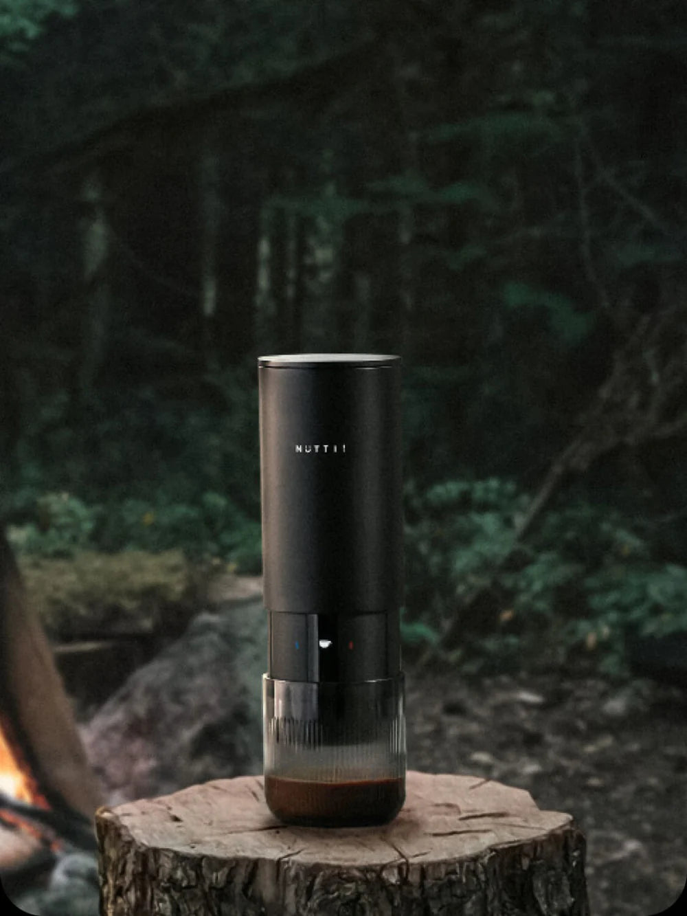 Black espresso machine on a wooden stump with a forest background