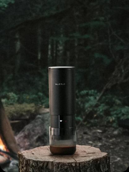 Black espresso machine on a wooden stump with a forest background