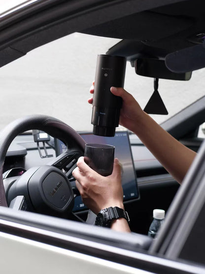 Person holding a black cylindrical device inside a car.