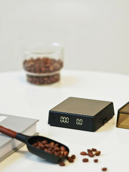 Digital kitchen scale with coffee beans on a white surface