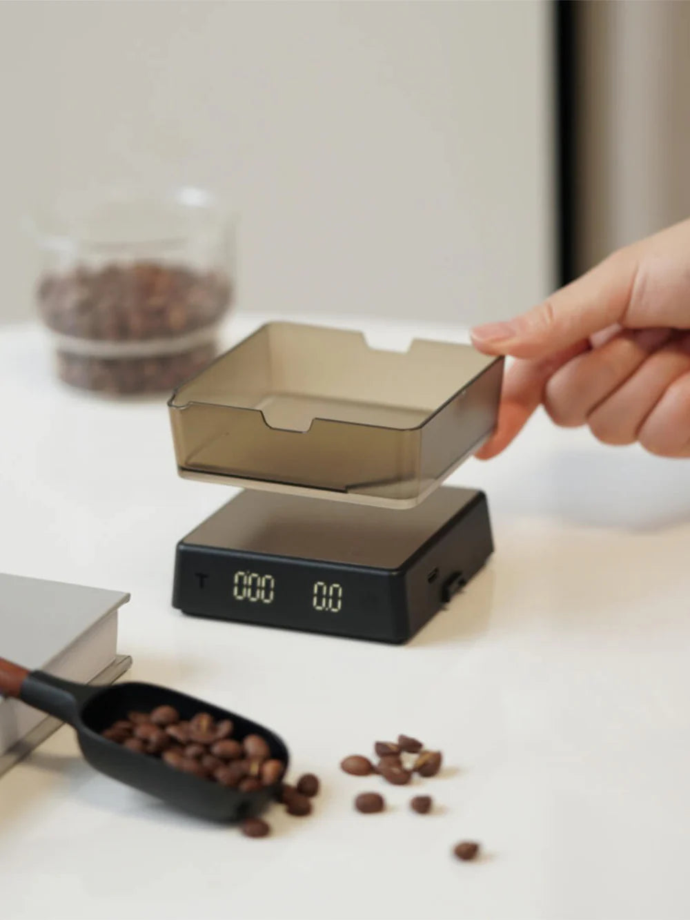 Hand interacting with a modern coffee scale on a kitchen counter.