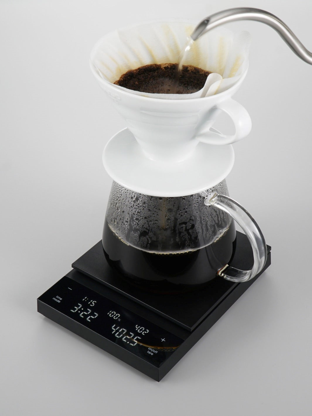 Black Hario coffee scale being used with a pour over dripper and gooseneck kettle