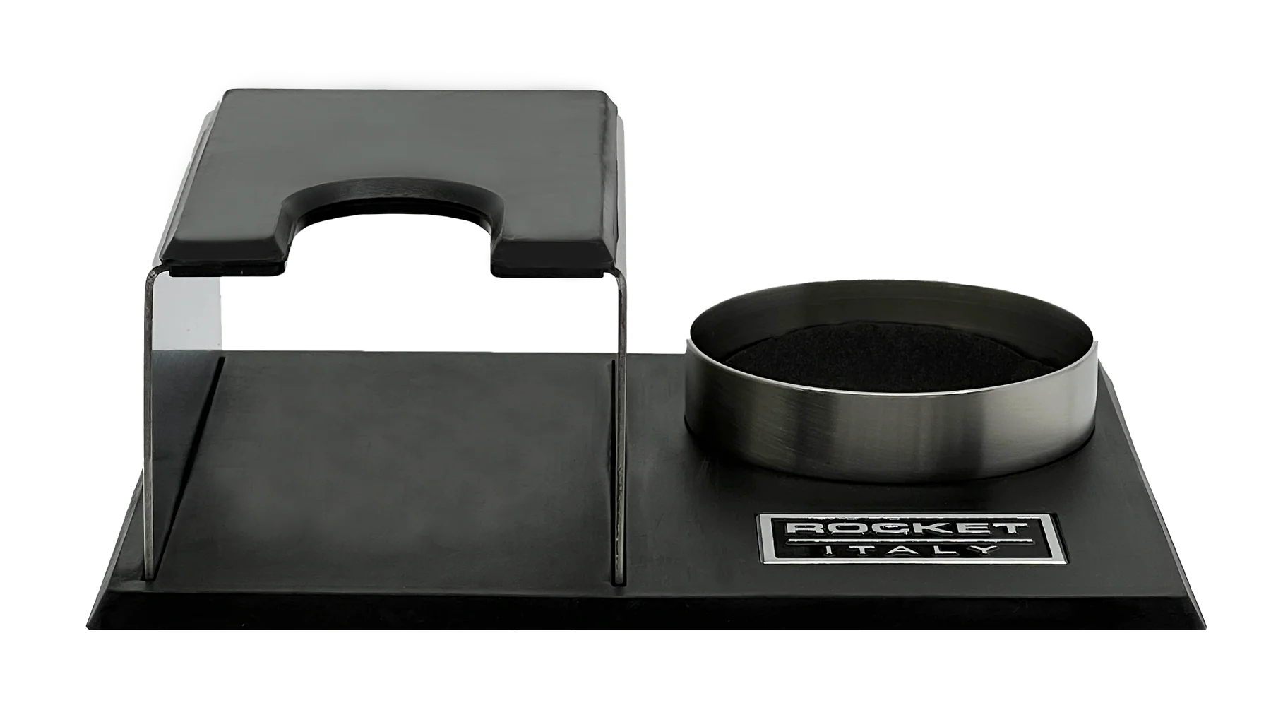 A Rocket Espresso Milano espresso tamping station featuring a brushed stainless steel body with black rubberized elements and a matching metal tamper holder on a black base. Front view.