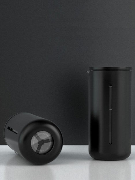 Two black cylindrical containers on a reflective surface with a dark gray background