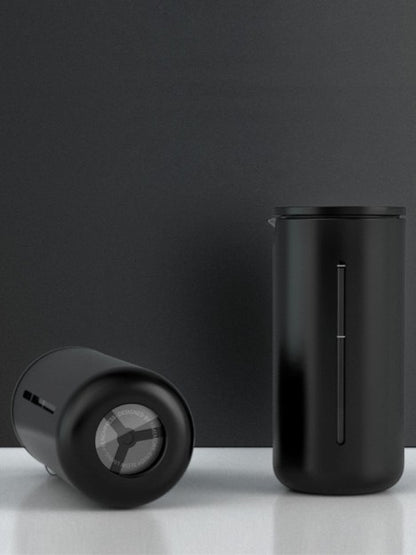 Two black cylindrical containers on a reflective surface with a dark gray background
