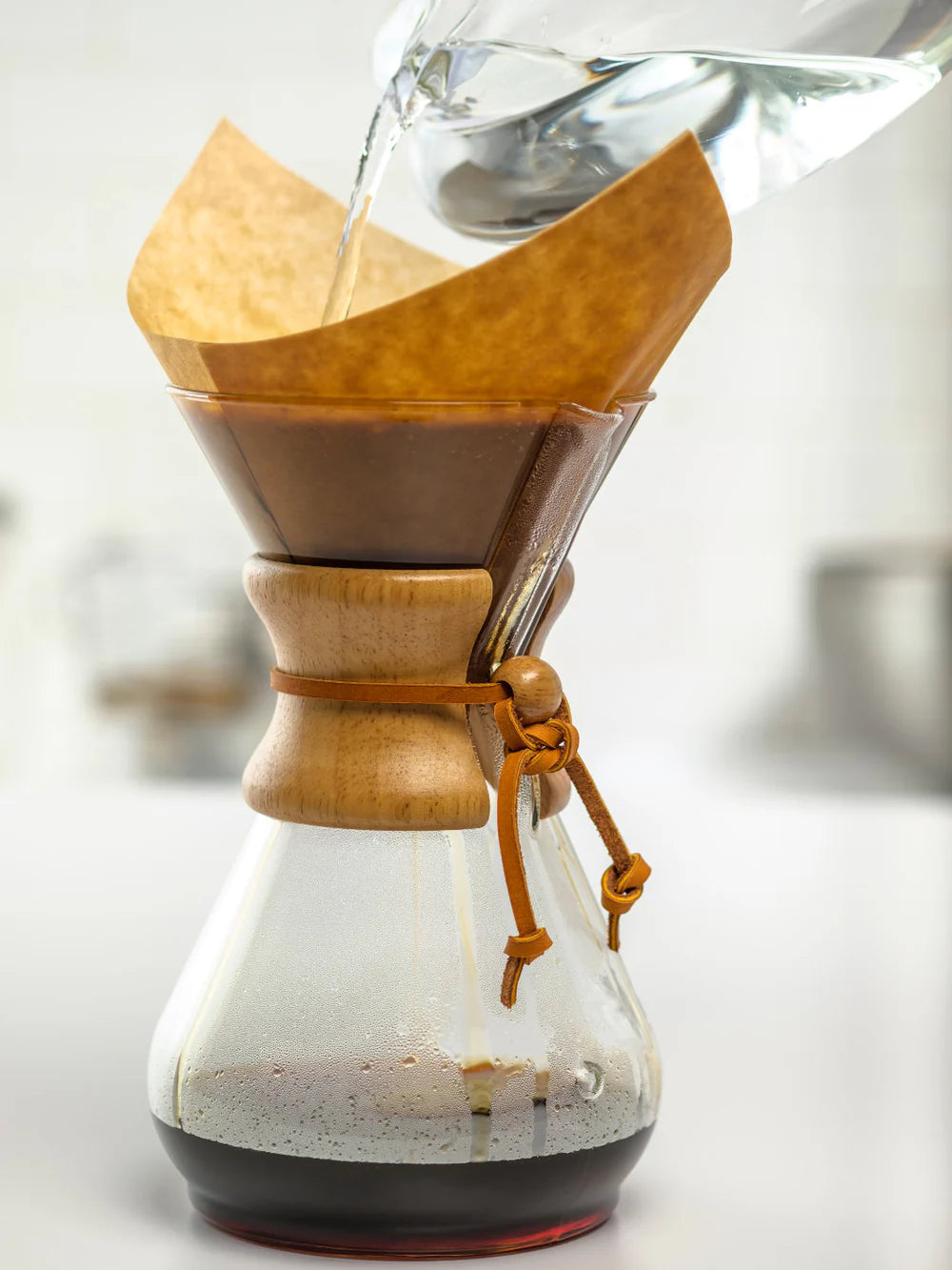 Glass coffee maker with wooden collar and filter on a white background
