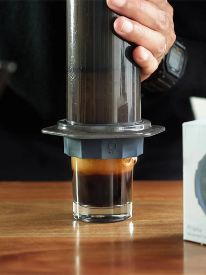 Person using an AeroPress to make coffee on a wooden surface