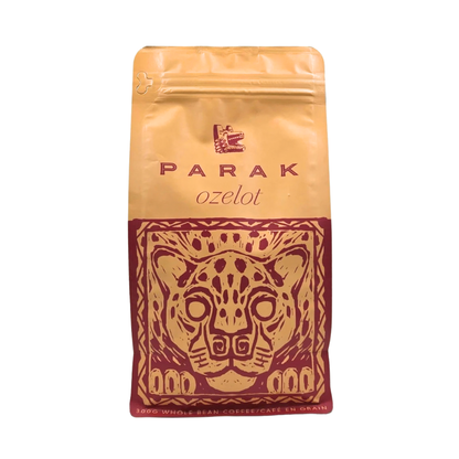 A stand-up pouch of Parak Ozelot coffee beans, featuring a gold and dark red design with a stylized jaguar head illustration.